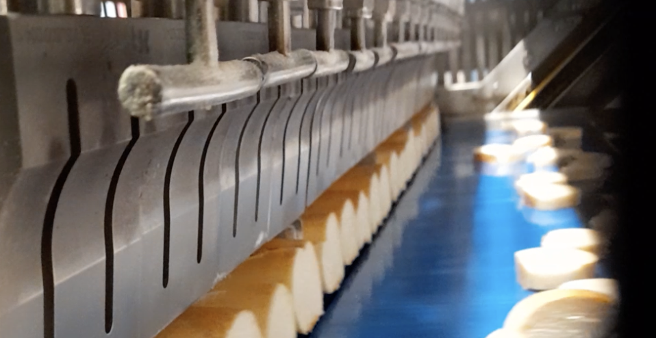 Detalle de hoja de titanio cortando barras de pan mediante tecnología de ultrasonidos de alta frecuencia.